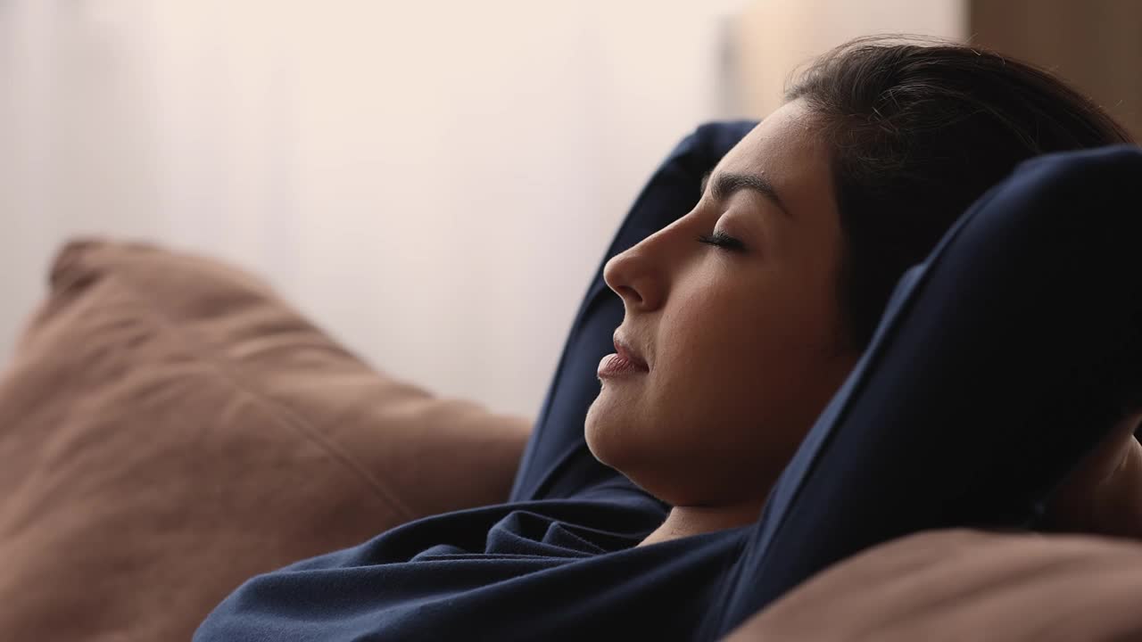 年轻的印度混血女子在沙发上做白日梦。视频素材