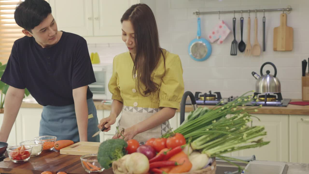 新婚夫妇互相帮忙做饭，在家里玩得开心。夫妻花时间一起做可爱的、快乐的饭菜。视频素材