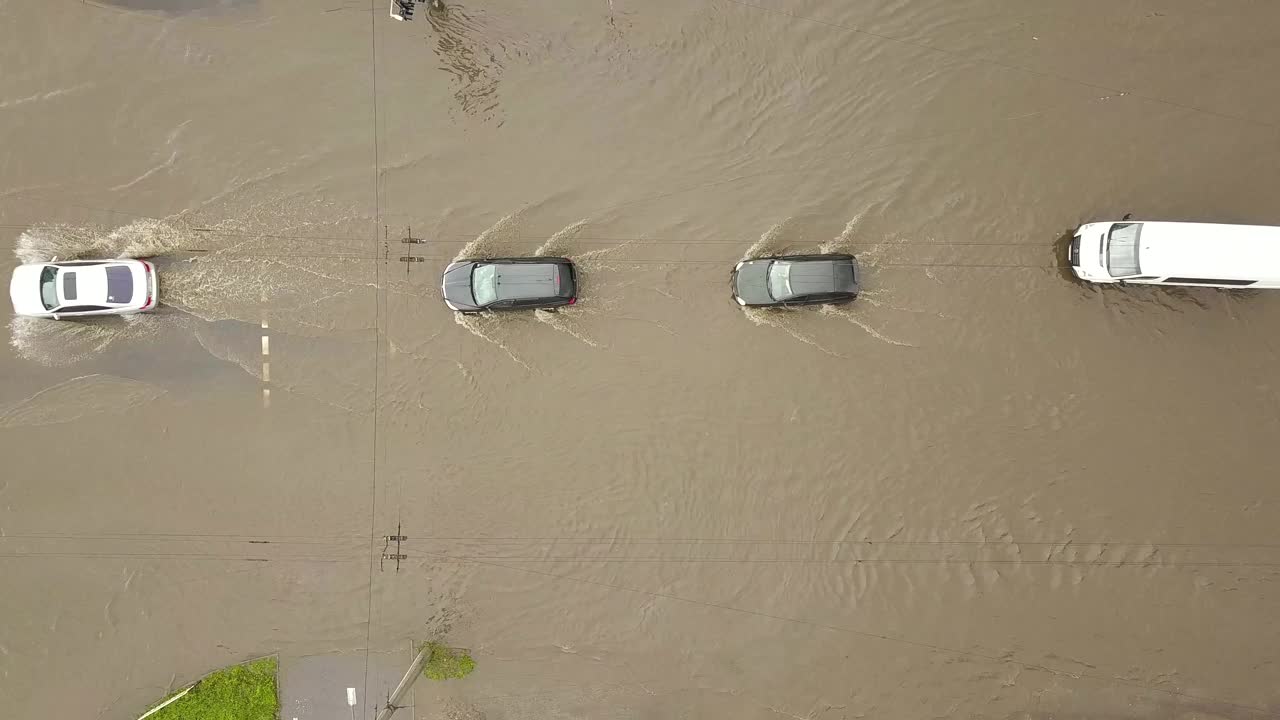 交通车辆在被雨水淹没的道路上行驶的鸟瞰图。视频素材