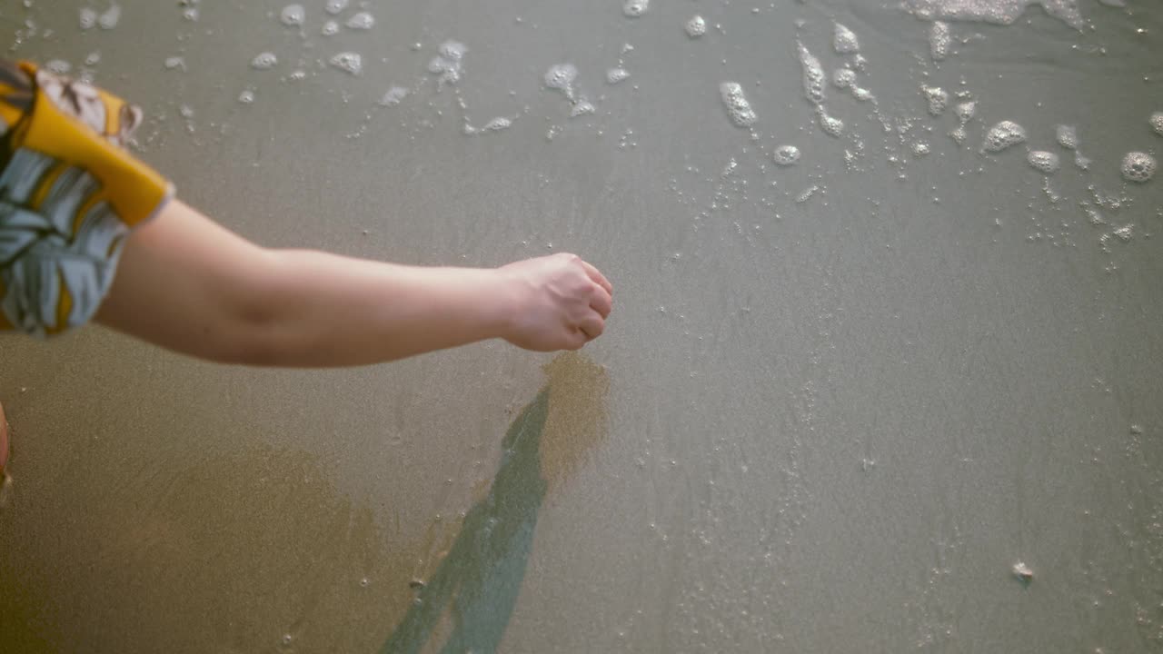 靠近女女人的手在沙滩上画心和海浪清除在海岸上的心旅行的概念视频素材