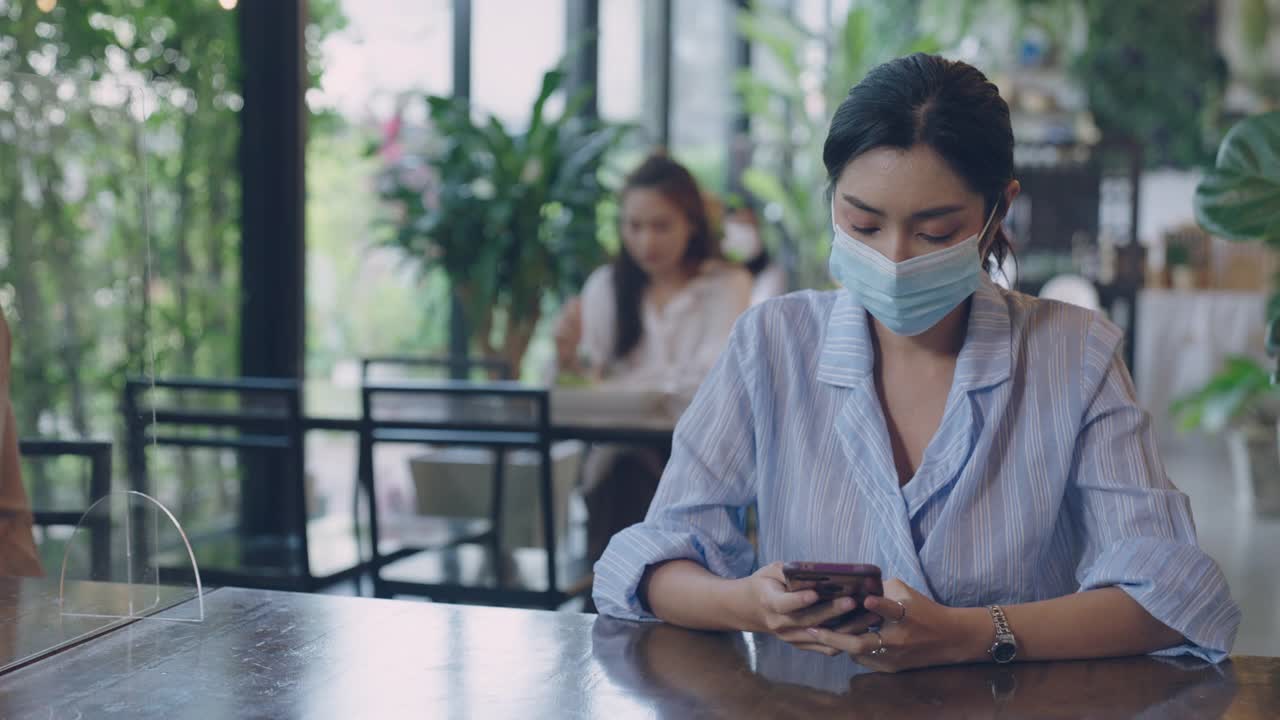 年轻的亚洲女性分开坐在餐厅吃饭和保持社交距离视频素材