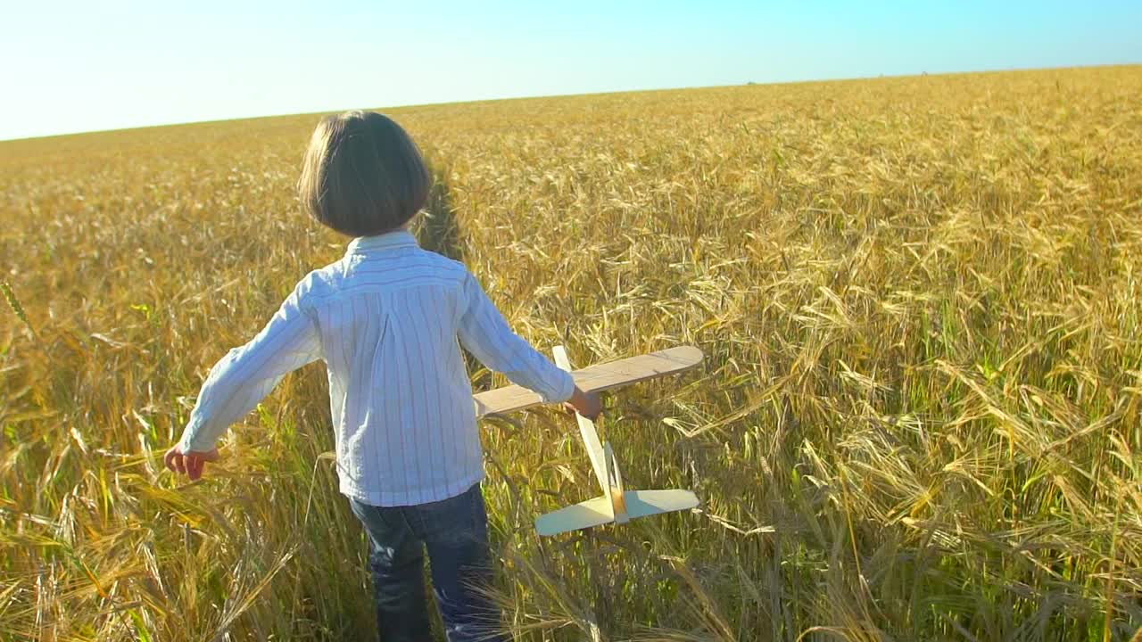 快乐的小男孩和玩具飞机在麦田在日落。孩子们在夏天的户外玩飞机。梦想飞行的小飞行员，和幸福的家庭一起度假。大的梦想视频素材