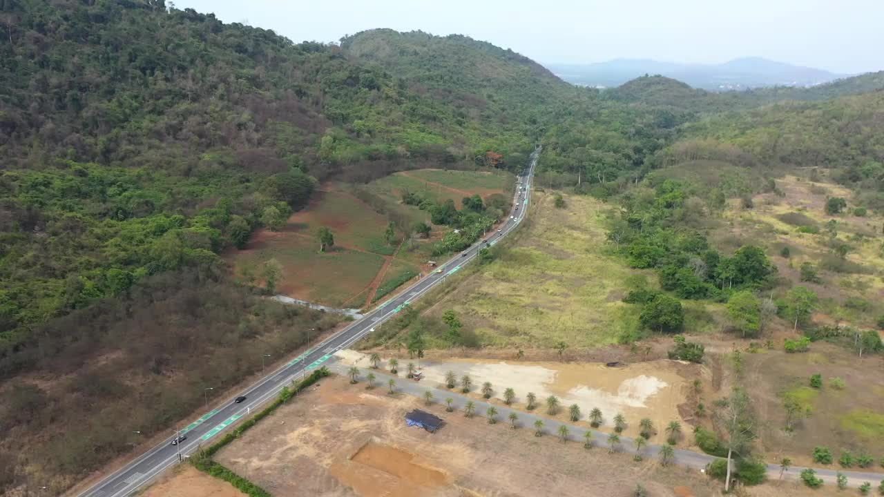 有一条小岔路，路旁有森林和青山，公路上车辆行驶的鸟瞰图视频素材