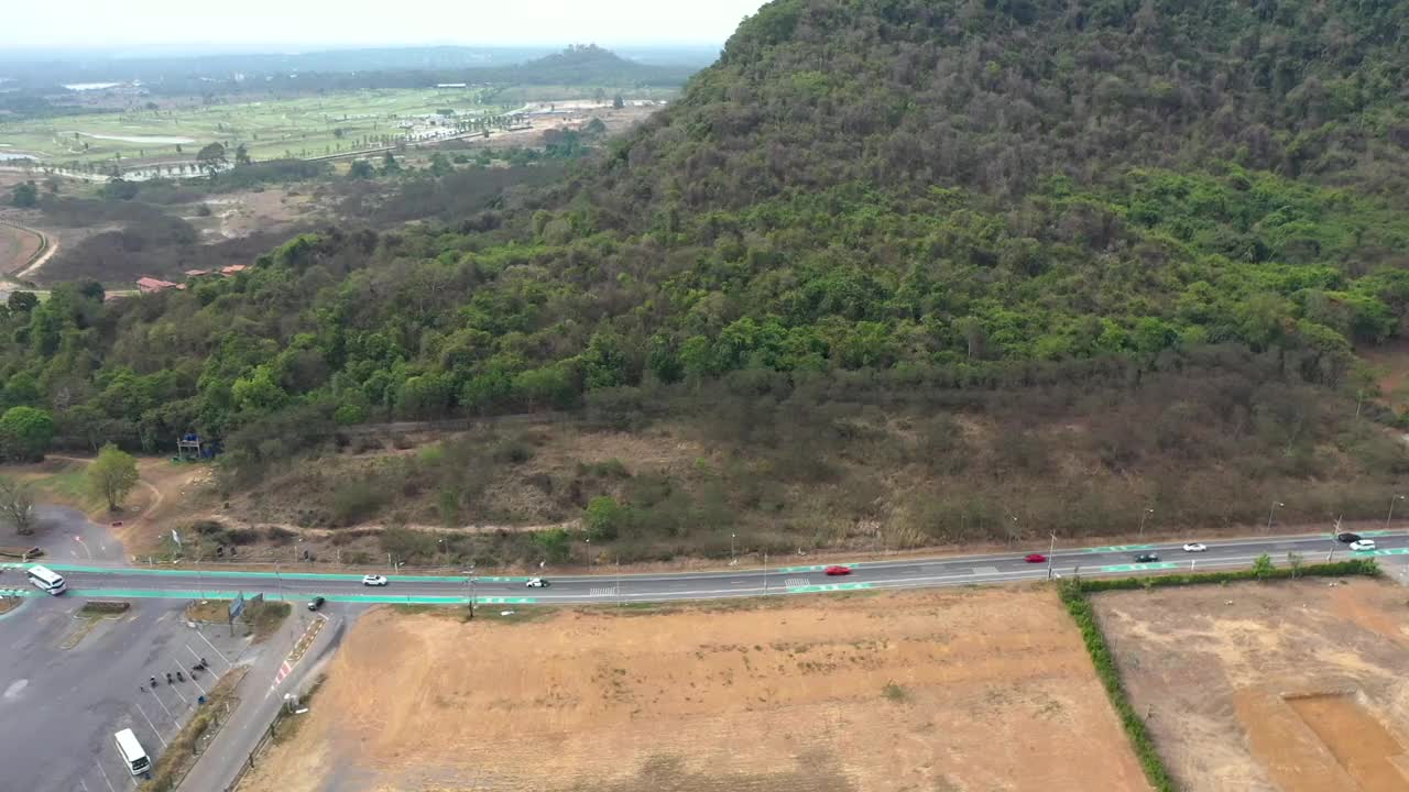 鸟瞰高速公路上行驶的汽车，山上有森林，路边有空地视频素材