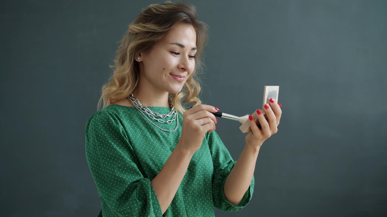 慢动作美丽的年轻女子化妆和微笑在灰色的背景视频素材