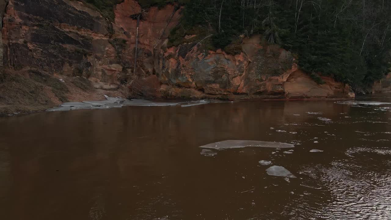 低角度:在美丽的沙崖附近的高佳河融化的雪和冰视频素材