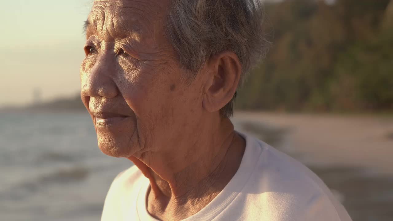 一位高级妇女在海上的肖像。她微笑着看着镜头。视频素材