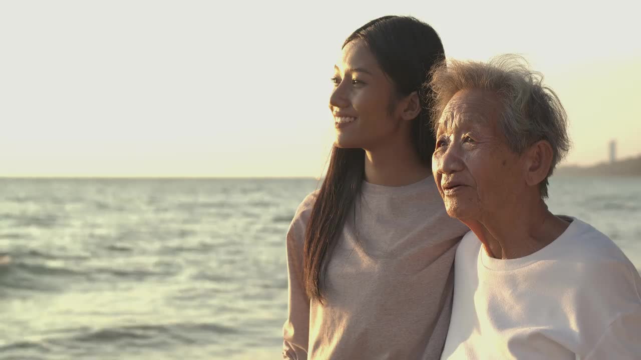 一个女人和她祖母在海边的肖像。他们笑着在一起聊天。视频素材