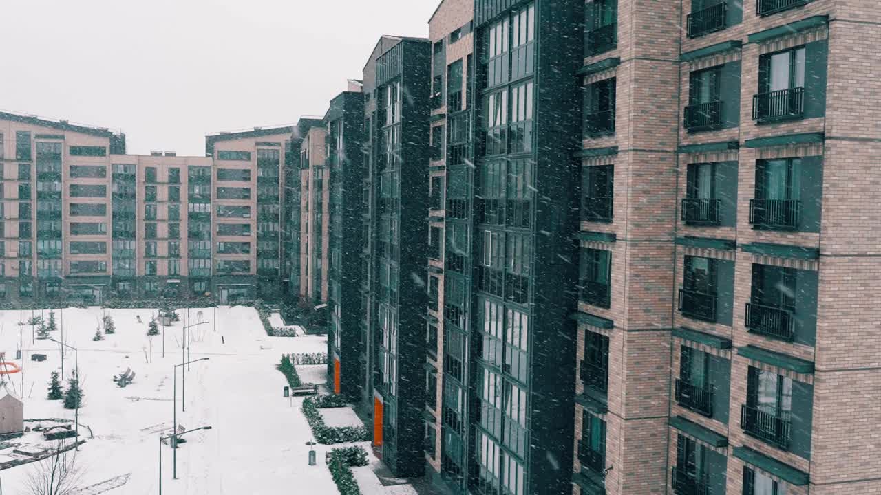 冬季景观与公寓大楼。多层住宅立面，庭院中雪花飘飘的景象。建筑城市住宅，房地产代理在现代，新，时尚的城市概念。视频素材