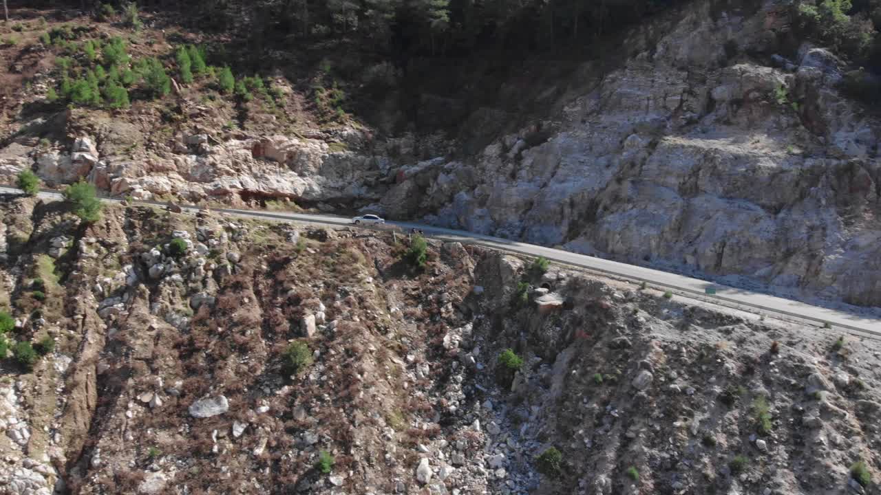 美丽的山景与雪山山峰，无人机视图。单空车路穿过松林山口视频素材