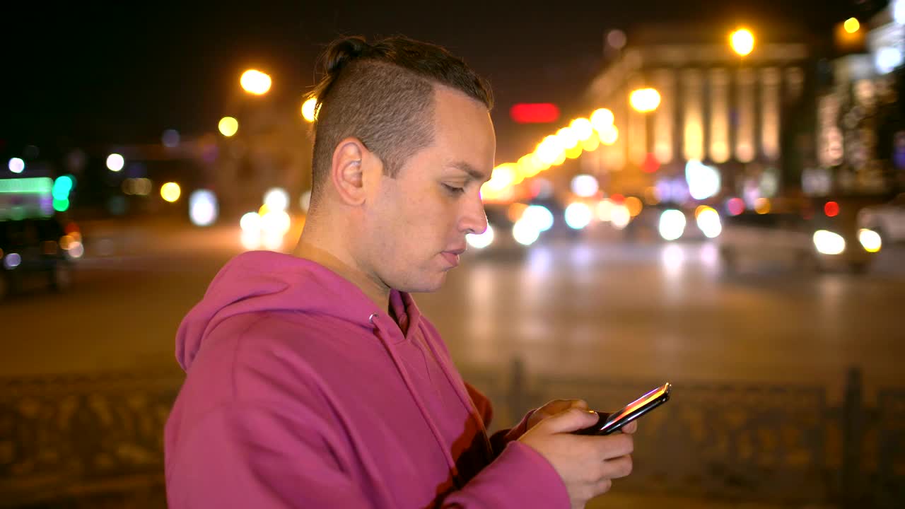 一名男子在夜市用手机拍照。一个漫不经心的年轻人在外面用手机拍照视频素材