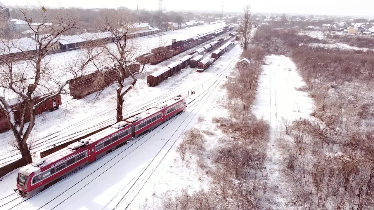 红色列车DMU离开车站鸟瞰图。冬季有积雪覆盖站。视频素材