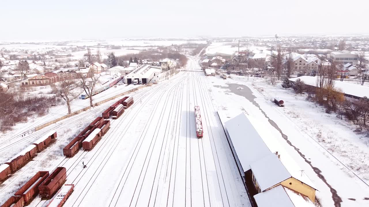 红色的柴油火车在火车站被雪覆盖着离开车站。视频素材