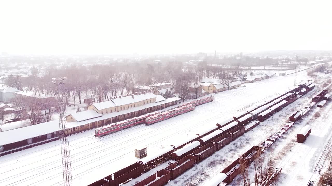 三辆同样的红色柴油火车在火车站被雪覆盖。一列火车正驶离车站。视频素材