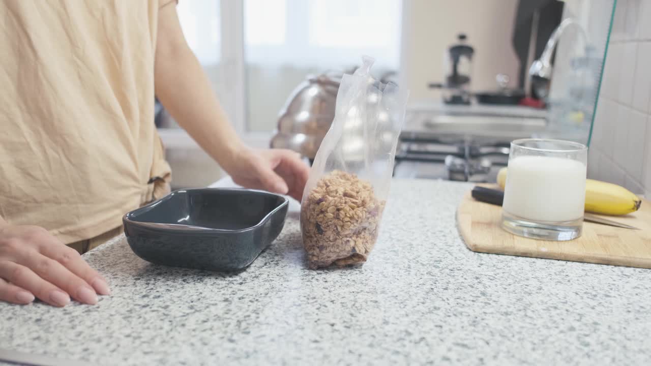 一个女人把燕麦卷倒进厨房的碗里。视频素材