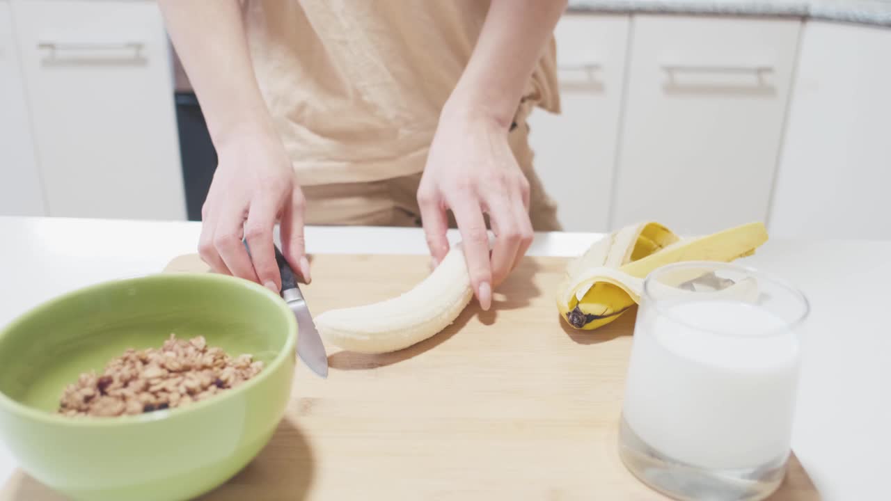 正在切香蕉做早餐的女人。视频素材