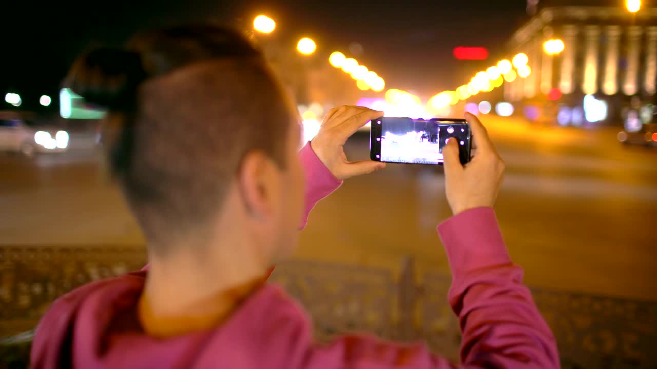 一名男子在夜市用手机拍照。一个漫不经心的年轻人在外面用手机拍照视频素材