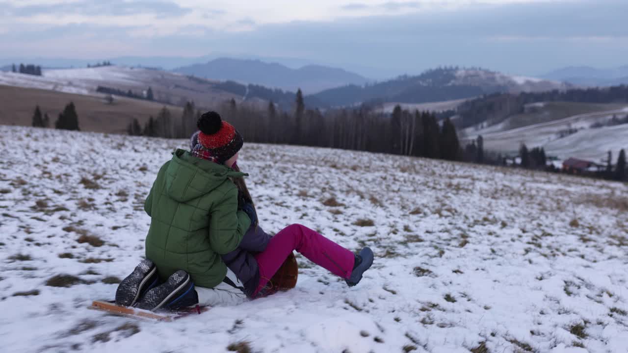 哥哥和妹妹在一个冬天的晚上在山上滑雪橇视频素材