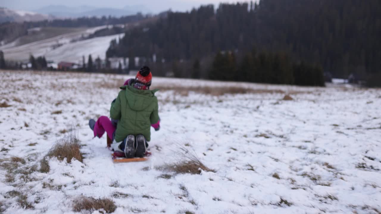 哥哥和妹妹在一个冬天的晚上在山上滑雪橇视频素材