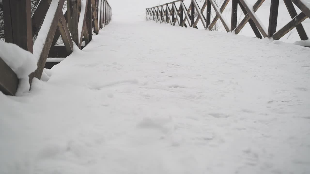 这是一座被雪覆盖的木桥的静态视频。雪花从上面落下来视频素材