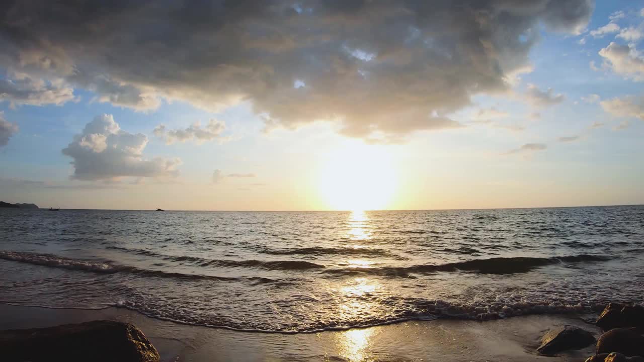 时间流逝的海和天空云景镜头。海浪在多石的海滩上激起涟漪。夕阳映照在海面上。视频素材