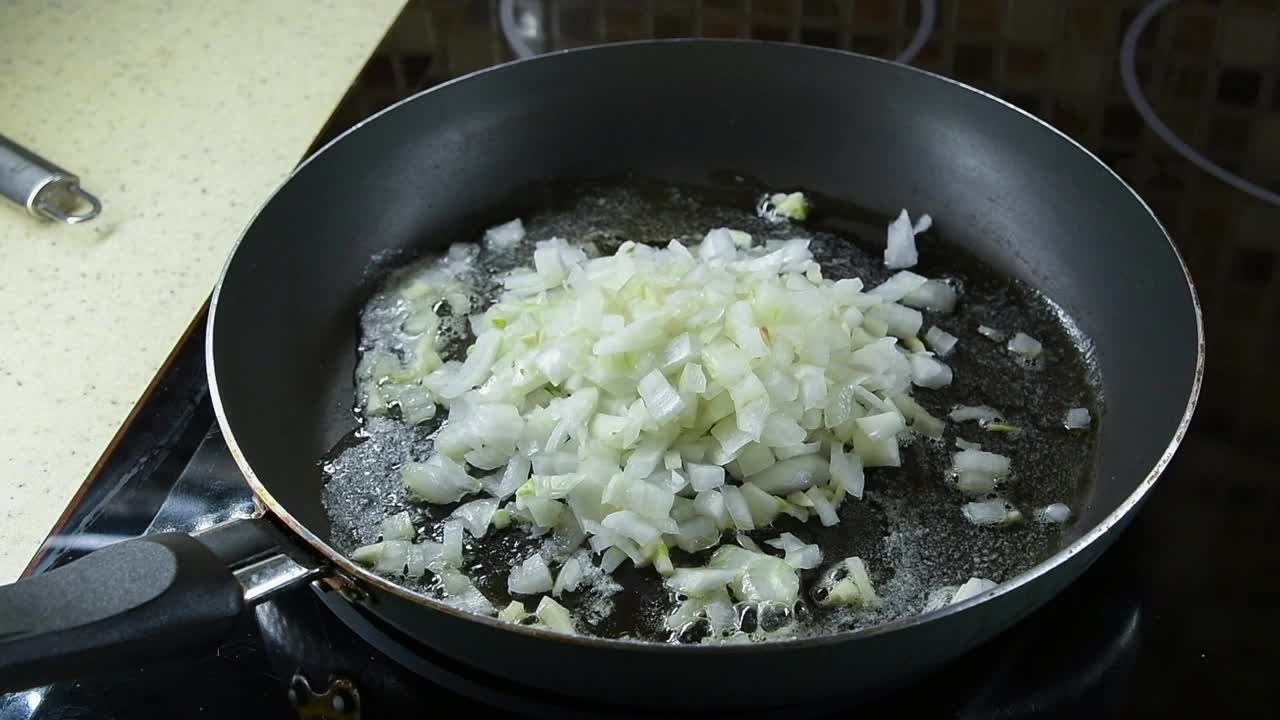 切碎的洋葱和大蒜在煎锅里炒视频素材