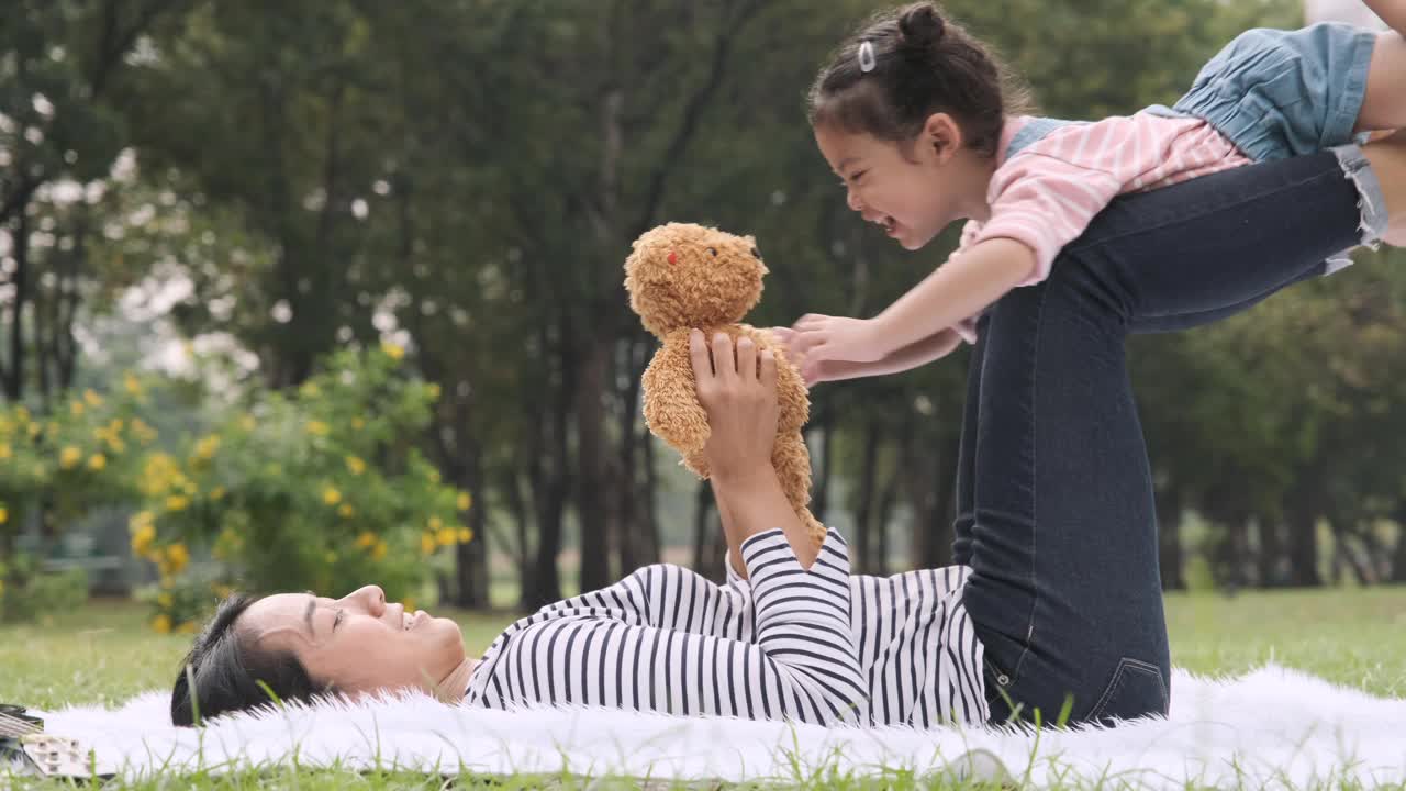 年轻的亚洲妈妈和她的小女儿在花园里玩，手握镜头。视频素材