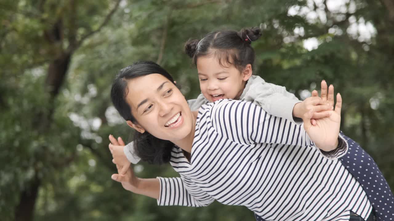 小女孩抱着妈妈的脖子开心地摇摆着，慢镜头拍摄。视频素材