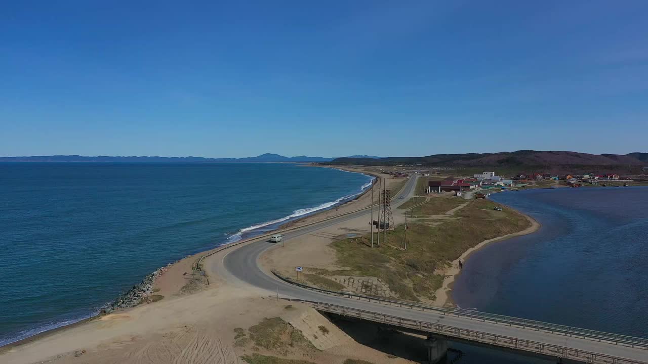 在蔚蓝的海面上，汽车在空旷的公路上行驶视频素材