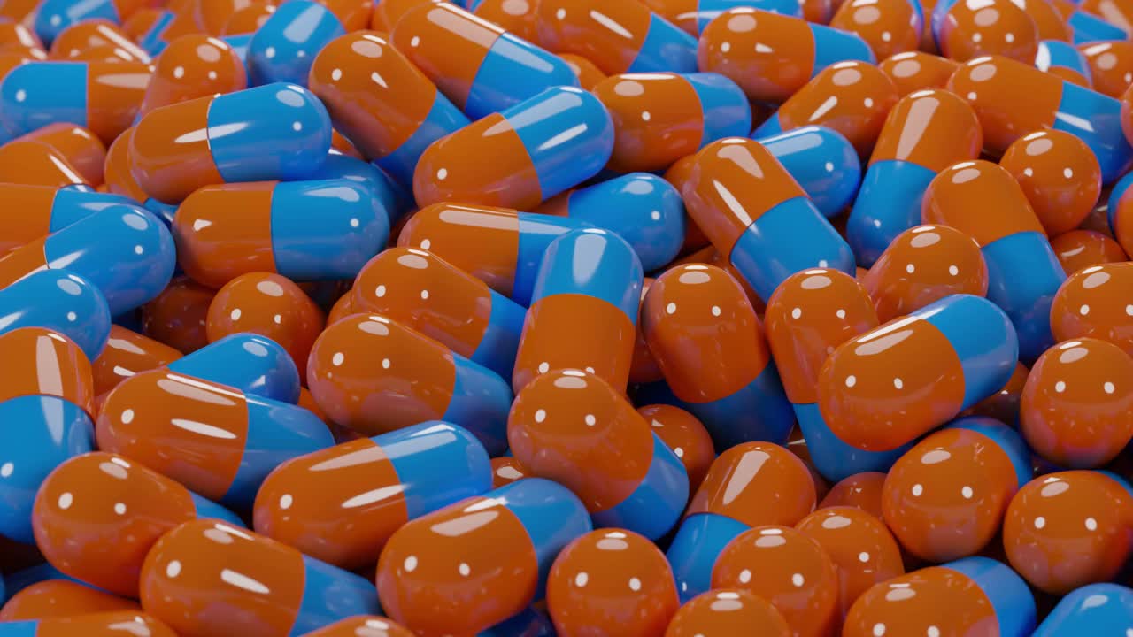 靠近堆蓝色和橙色的医药胶囊丸生产在一个工厂的3D渲染视频素材