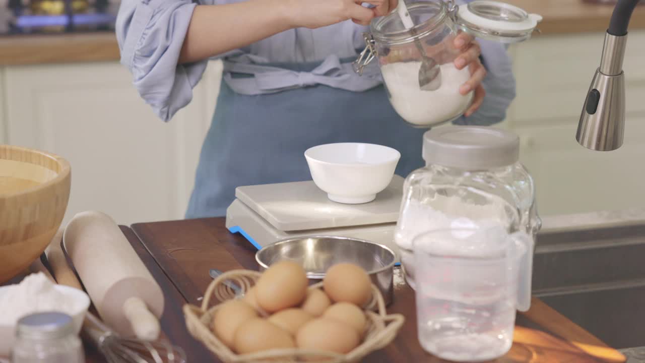 一个女孩的手从罐子里舀出糖来称量准备烘烤的原料视频下载