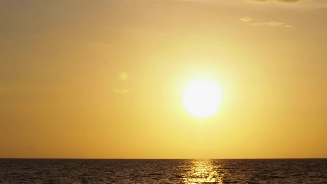 美丽日落的时间间隔。4k金色的天空，晴朗的天气。阳光在天空中的海景色。春天又大又圆又亮的太阳。B卷进尺背景视频素材