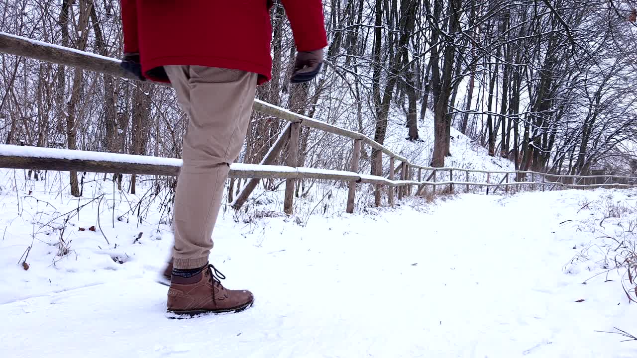 一个穿红色外套的人走在森林里的雪道上视频素材