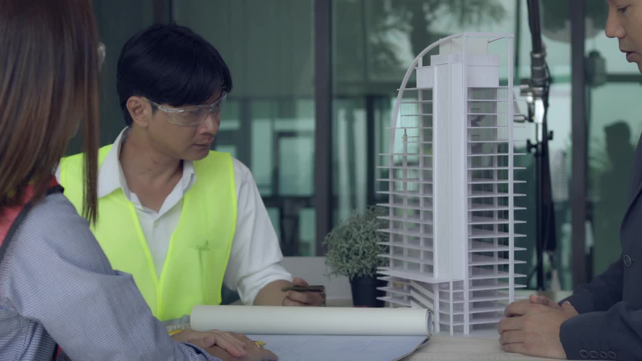 工程师或建筑师会议的建设概念，与合作伙伴和工程工具在工作现场的模型建造和蓝图。视频素材