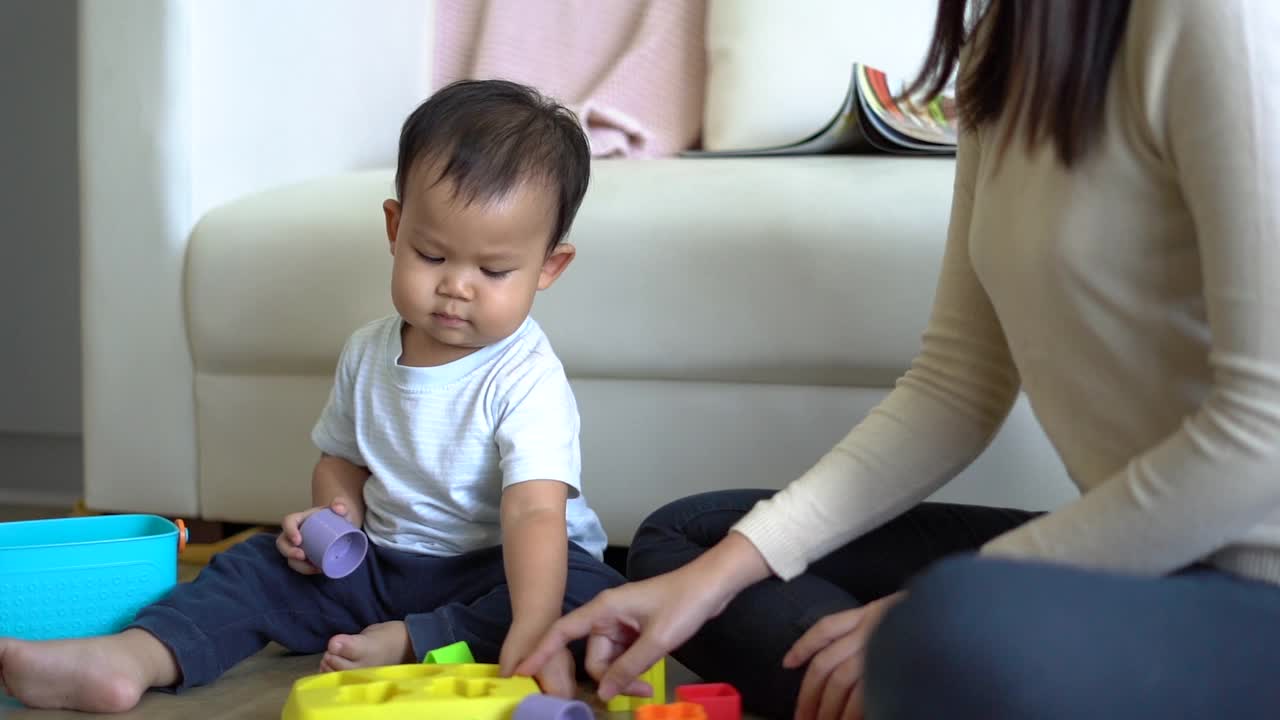 年轻的母亲和小男孩在家里沙发附近的地板上玩耍。幸福的家庭。视频素材