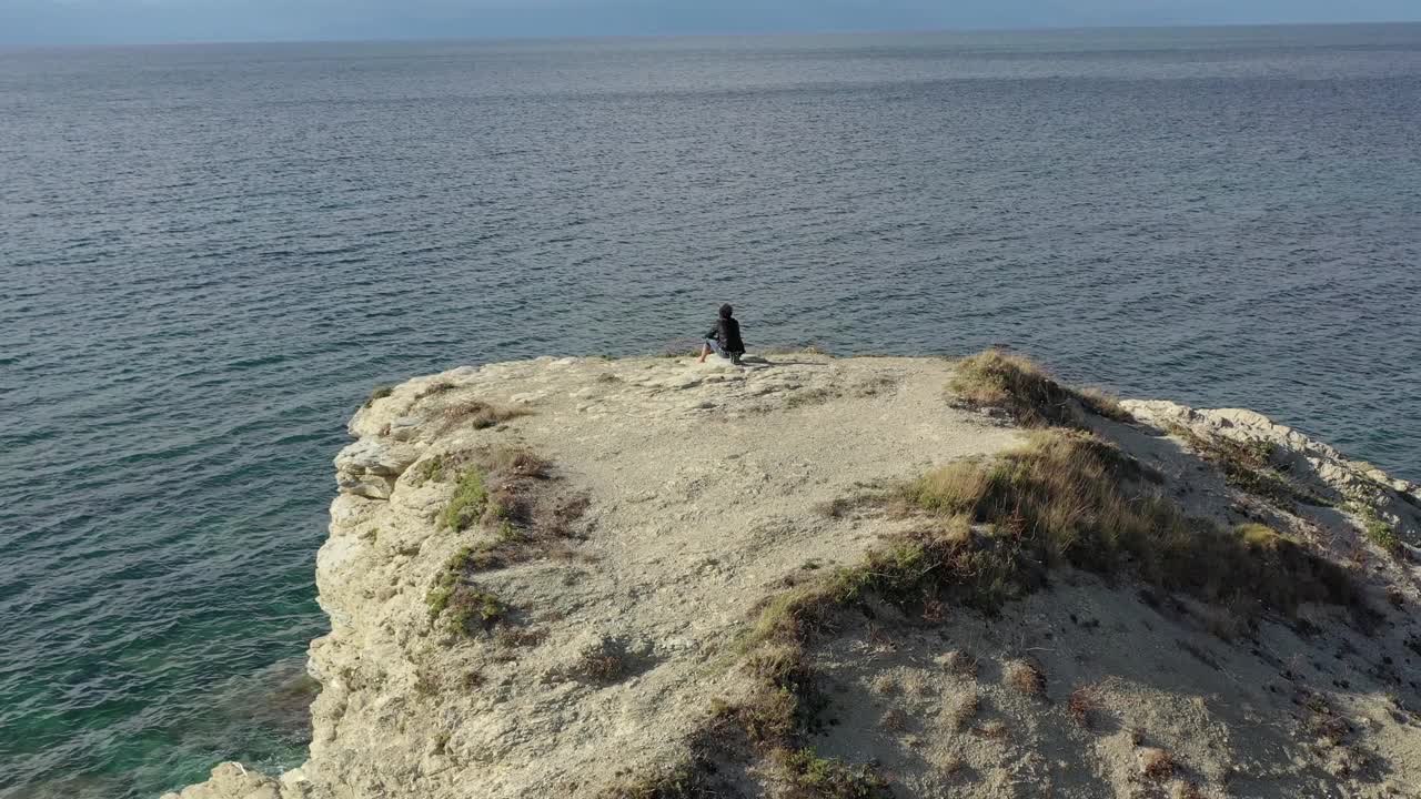 沉思的男孩在一块大岩石上欣赏着大海的地平线视频素材