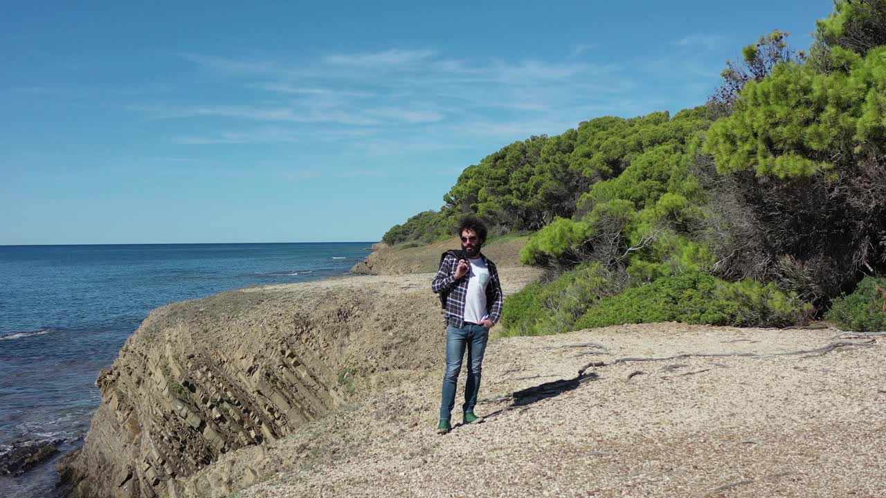 男孩在海边的悬崖上安详地行走。视频素材