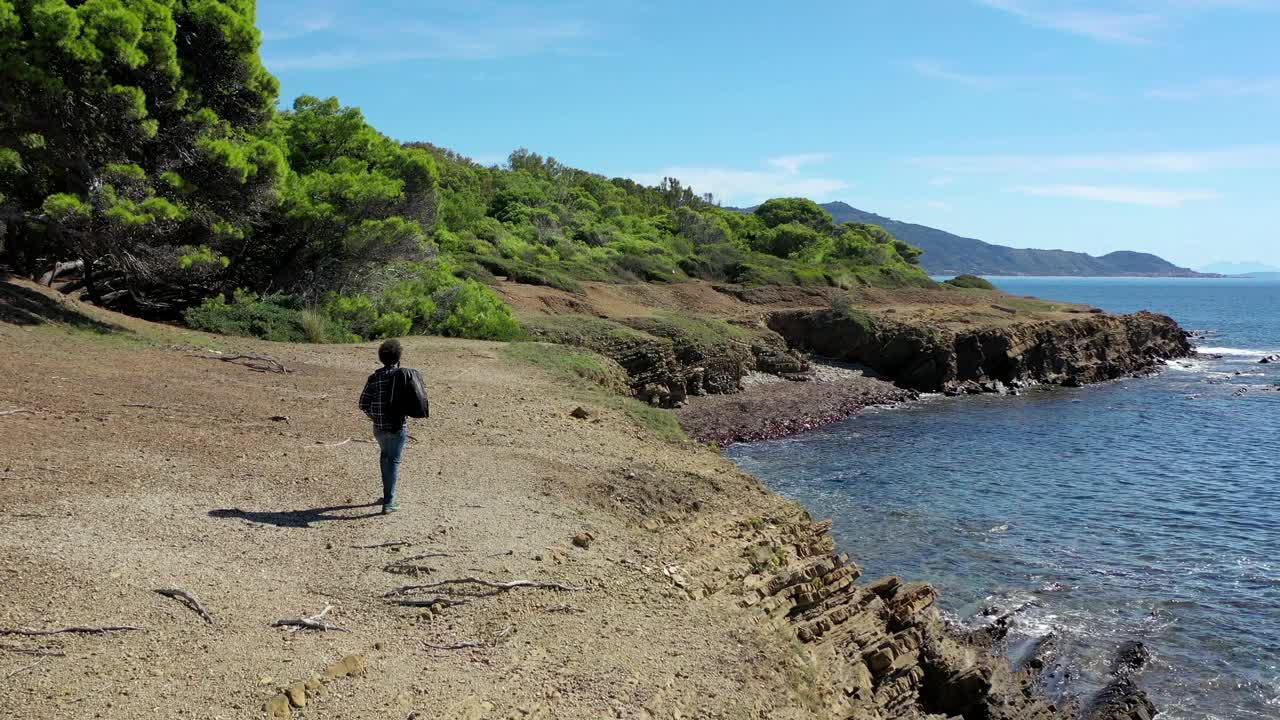 男孩在海边的悬崖上安详地行走。视频素材