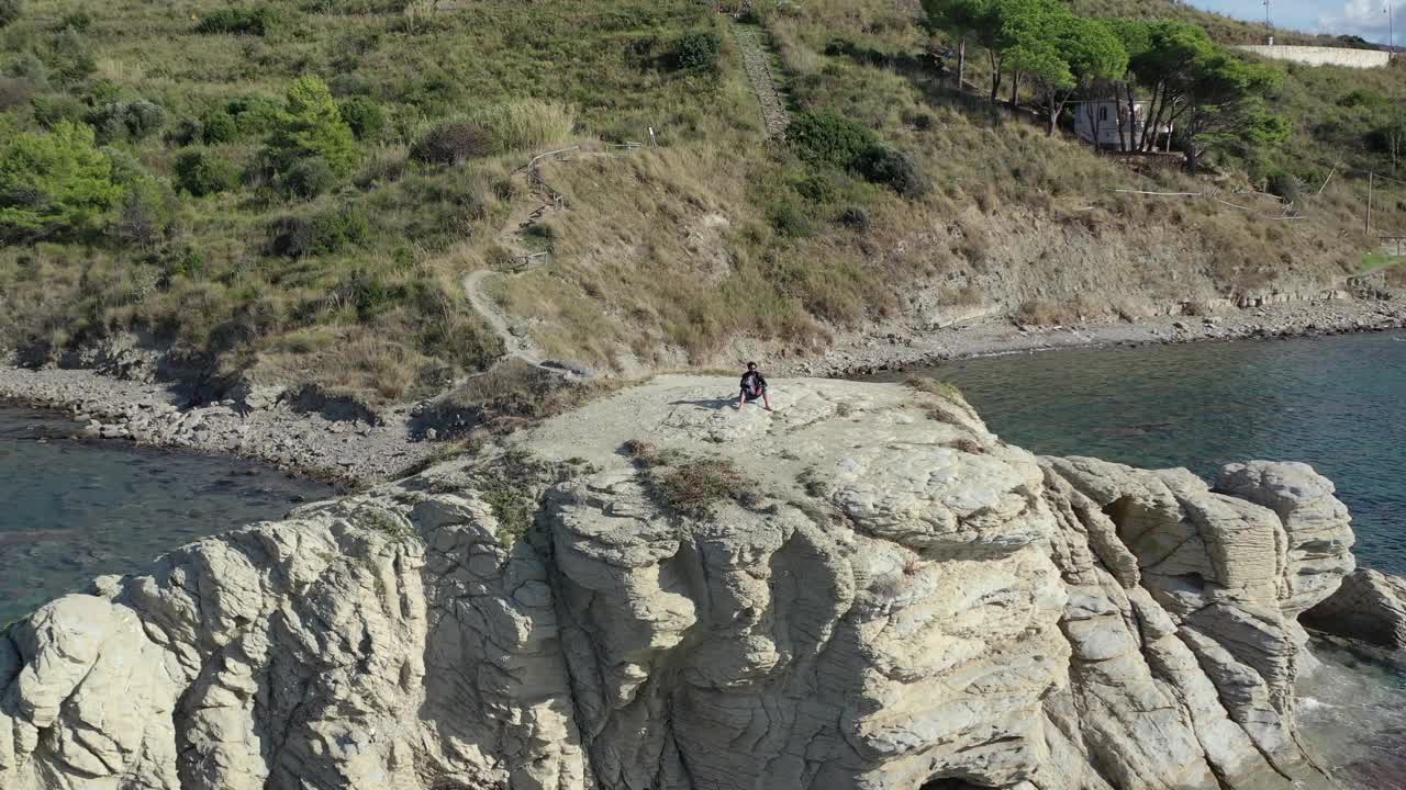 沉思的男孩在一块大岩石上欣赏着大海的地平线视频素材