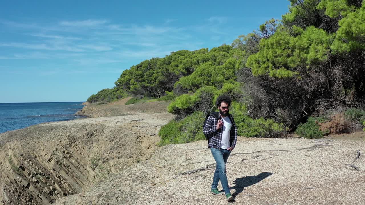 男孩在海边的悬崖上安详地行走。视频素材