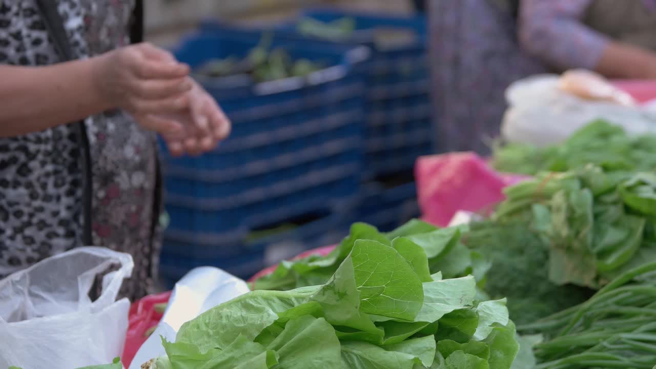 女人在食品市场购买新鲜的绿色菠菜的特写。视频素材