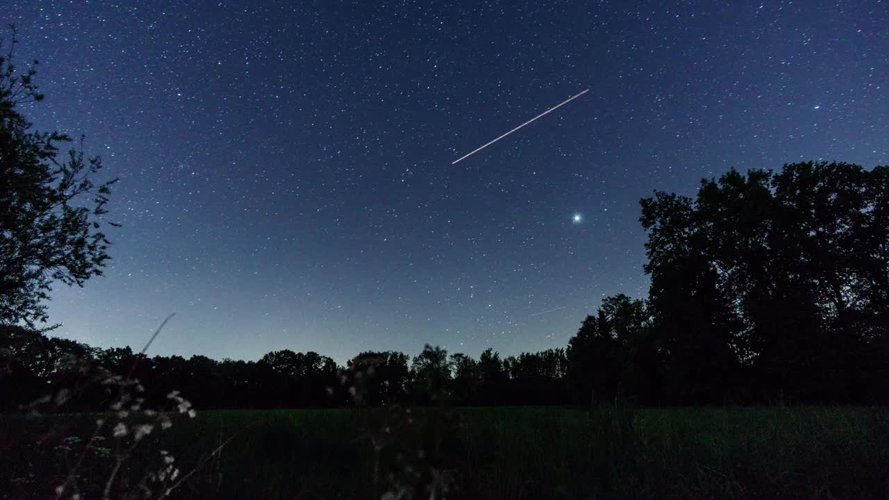 移动的银河和夜空中星星的轨迹，乡村风景和树木的剪影视频素材