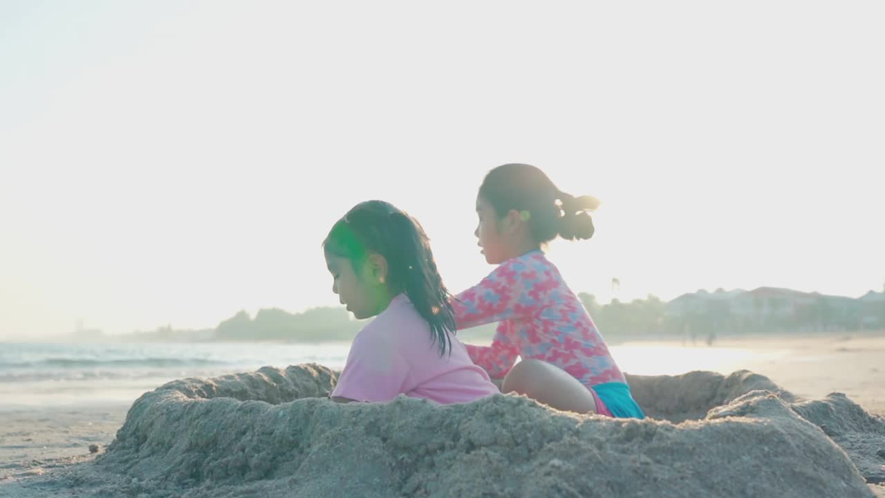 夏天，孩子们和朋友们一起在海滩上堆沙堡视频素材