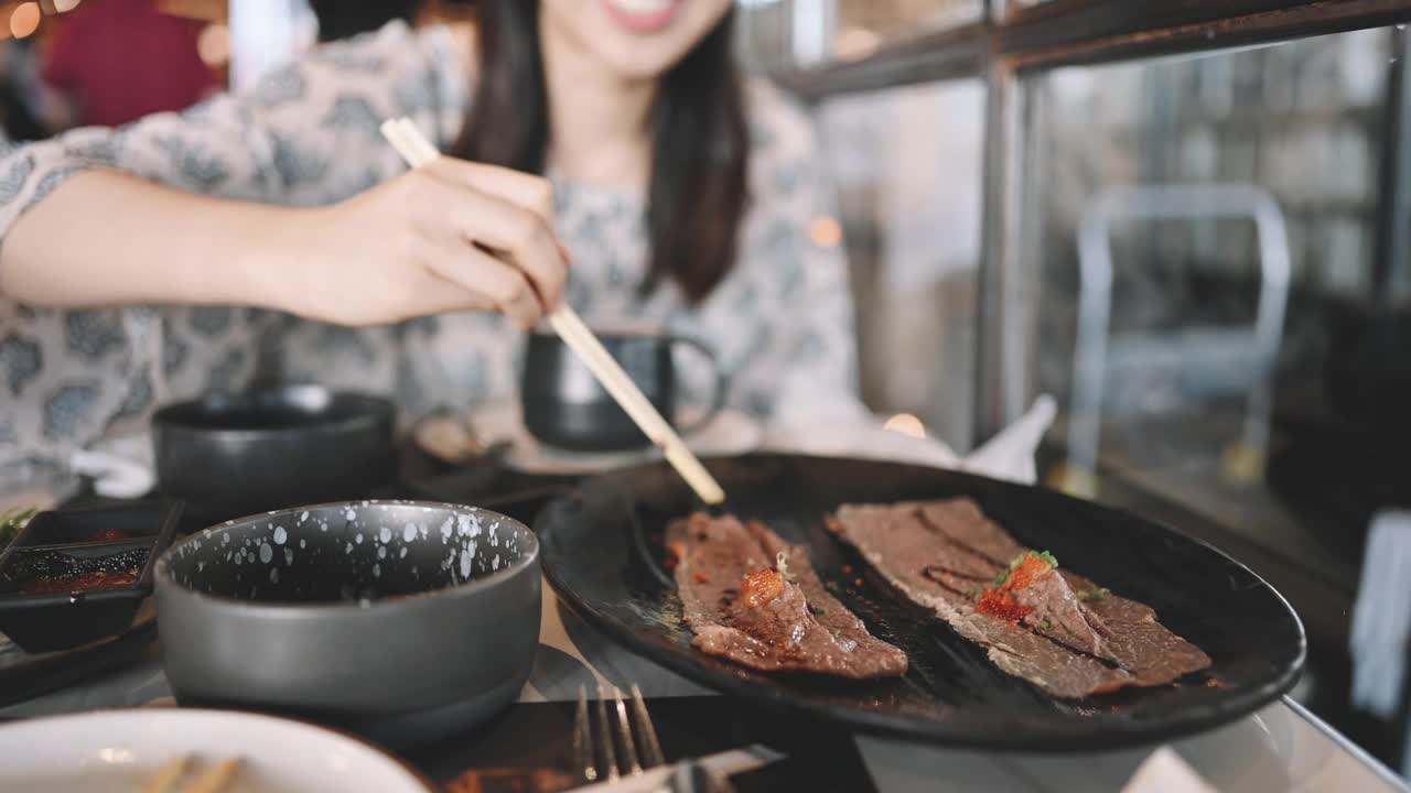 亚洲女性用餐时很乐意吃和牛寿司自助餐，烤冲绳牛肉配酱汁视频素材