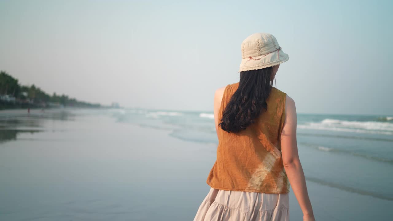 慢镜头女人的脚赤脚走在沙滩在金色的夕阳留下脚印。暑假里的女游客，在太阳下穿着美丽的波浪裙的女人视频素材