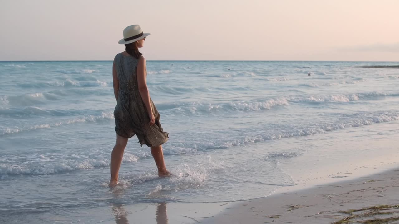 漂亮女人在海边休息。赤脚女模特在海浪中行走。视频素材