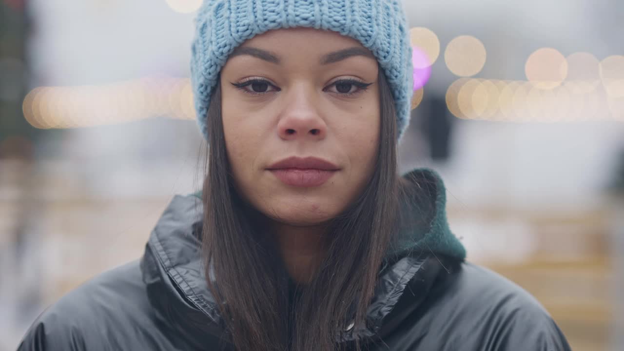 漂亮的年轻非洲裔美国女人的大头照片与棕色眼睛看着相机微笑。特写的自信美丽的千禧摆姿势在雾蒙蒙的冬天户外。美丽和温柔。视频素材