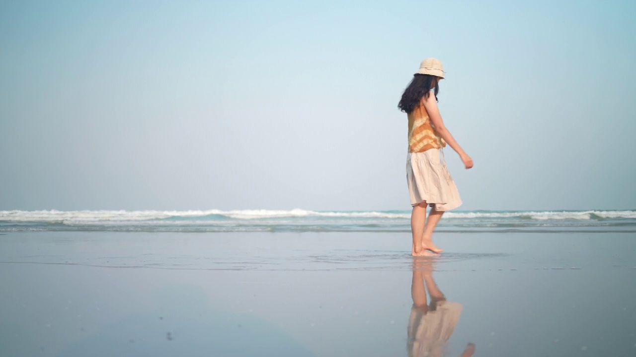 慢镜头女人的脚赤脚走在沙滩在金色的夕阳留下脚印。暑假里的女游客，在太阳下穿着美丽的波浪裙的女人视频素材