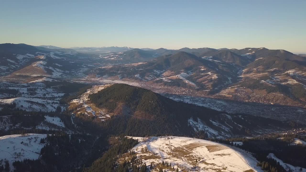 鸟瞰图上的小村庄，在冬天被雪覆盖的山丘上散落着房屋，裸露的喀尔巴阡山脉在乌克兰。视频素材