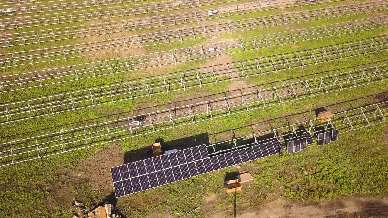 绿地上正在建设的太阳能发电厂鸟瞰图。用于生产清洁生态能源的电池板的组装。视频素材